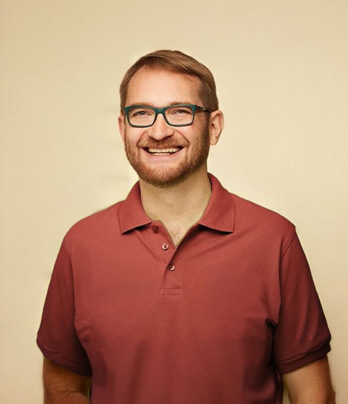 Freundliches Portrait von Dr. Ermark in einem bordeauxroten Polo, vor warmweißem Hintergrund – Kinderarzt in Landau